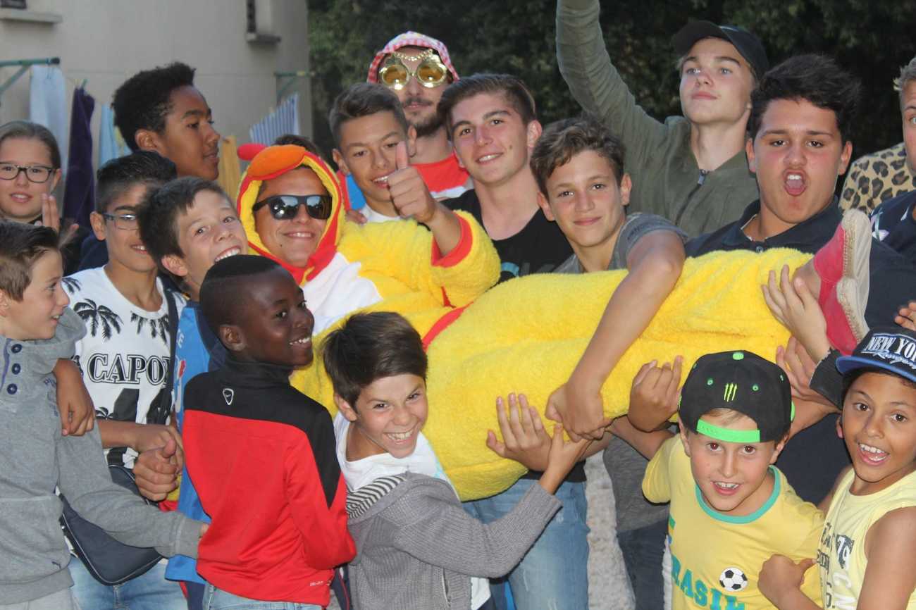 Photo d'un groupe d'enfant qui porte leur animateur déguisé en poussin jaune