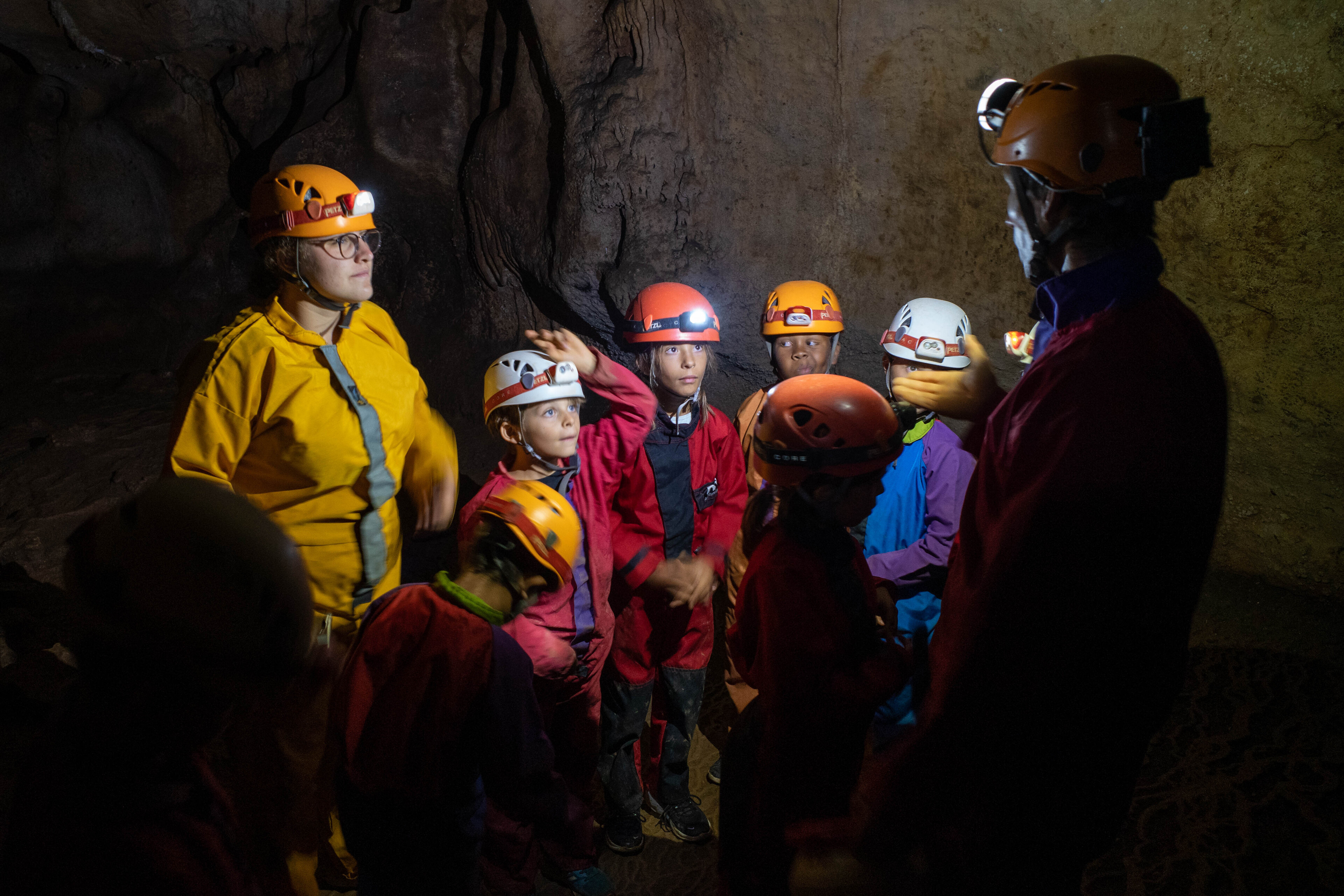 Photo de l'activité scolaire sport nature : la spéléologie, montrant un groupe d'enfant dans une salle sombre au cœur de la grotte
