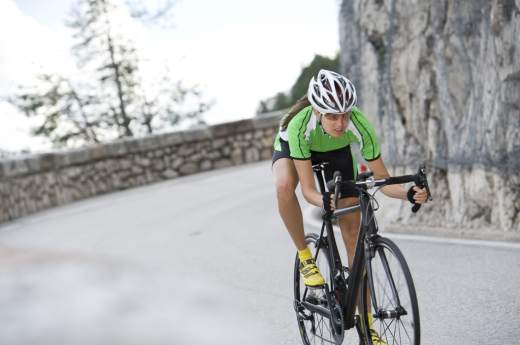 Cyclisme sur route Femme pratiquant le cyclisme sur une route de montagne illustrant la rubrique cyclisme sur route